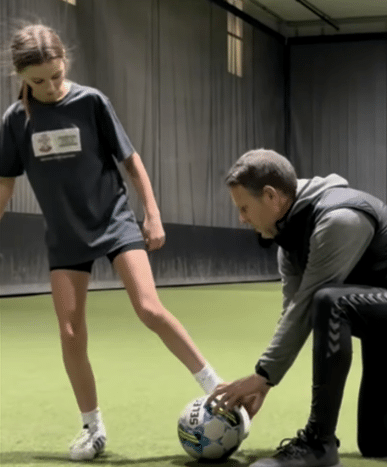 Coach demonstrating ball placement and foot positioning with a youth player during private 1-on-1 soccer training on turf.