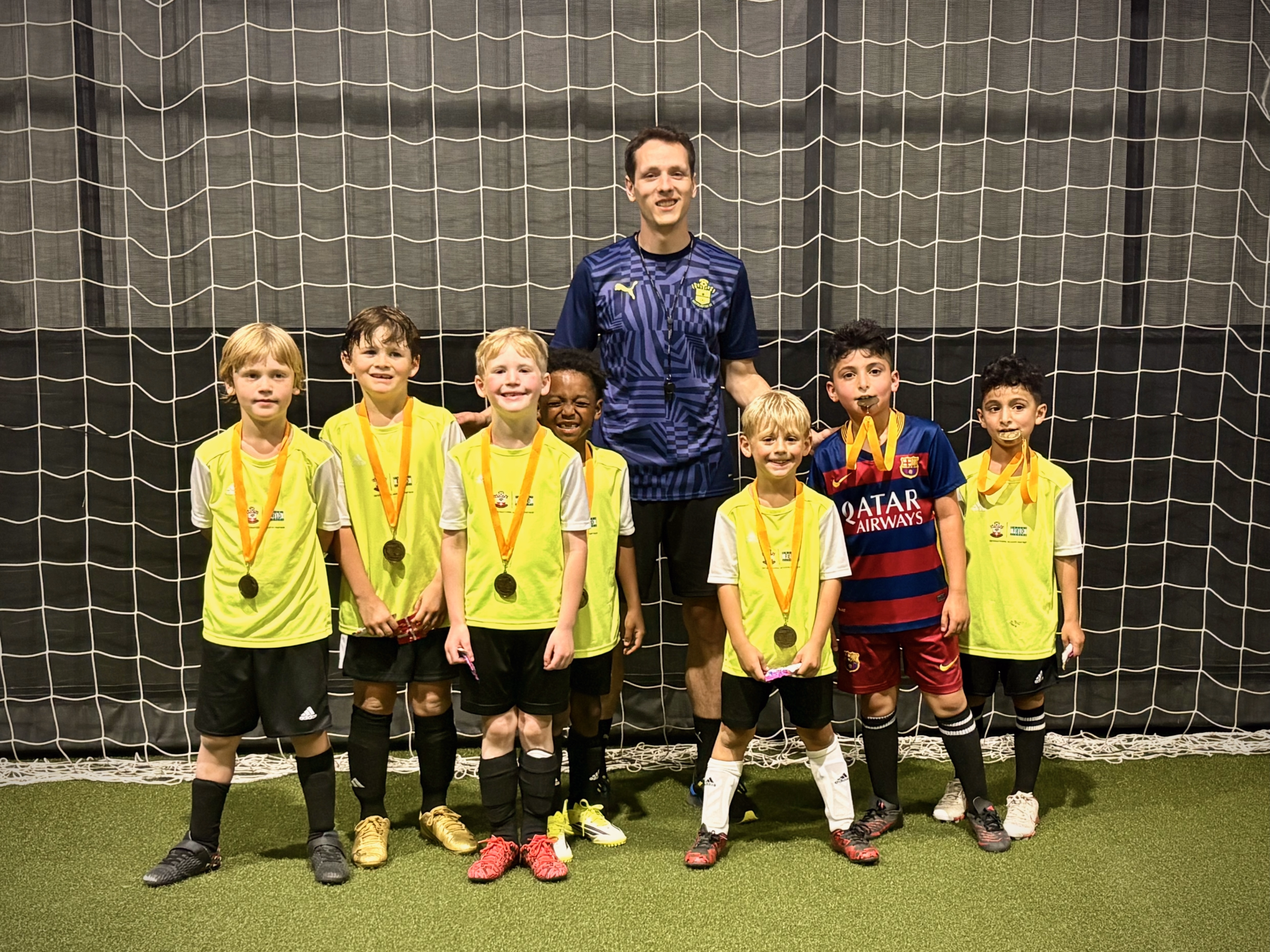 Soccer Field Academy Rec+ youth players with their season-end medals, posed with their coach inside the indoor facility in Bexley, Ohio