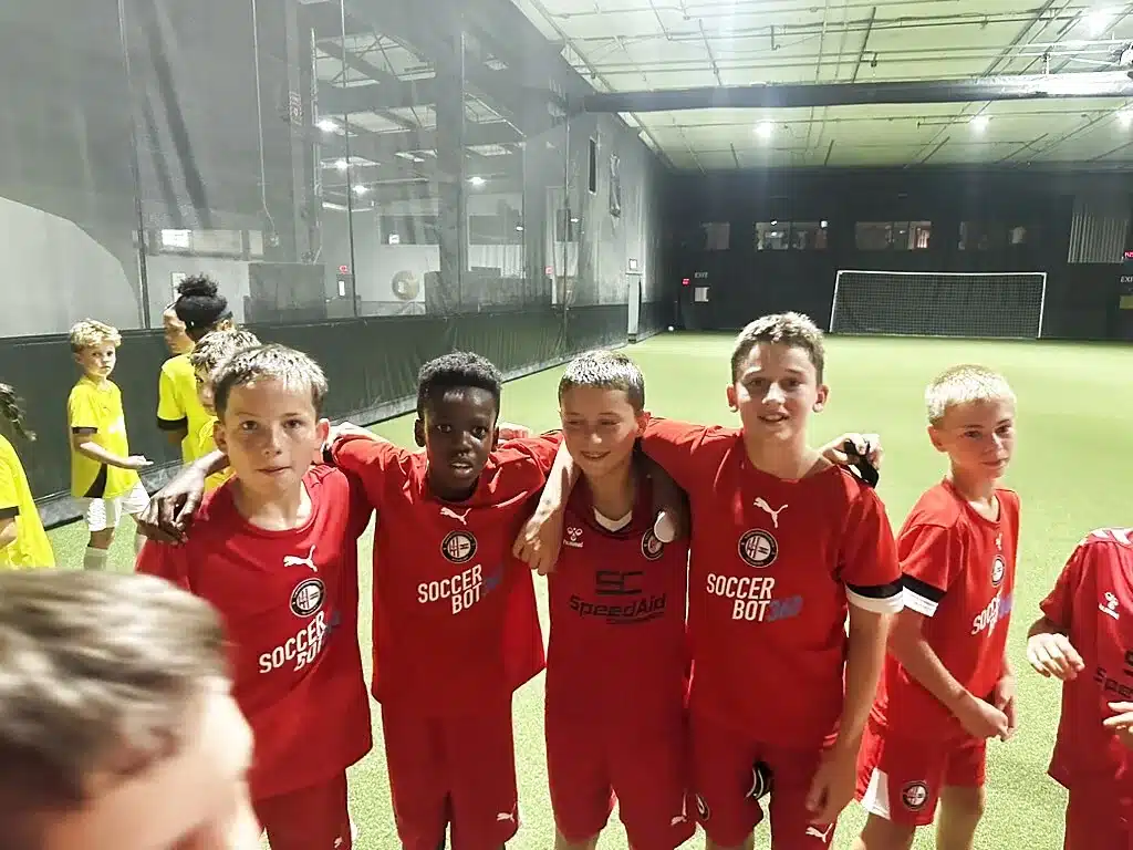 Youth players celebrating on the indoor turf field at Soccer Field Academy in Columbus
