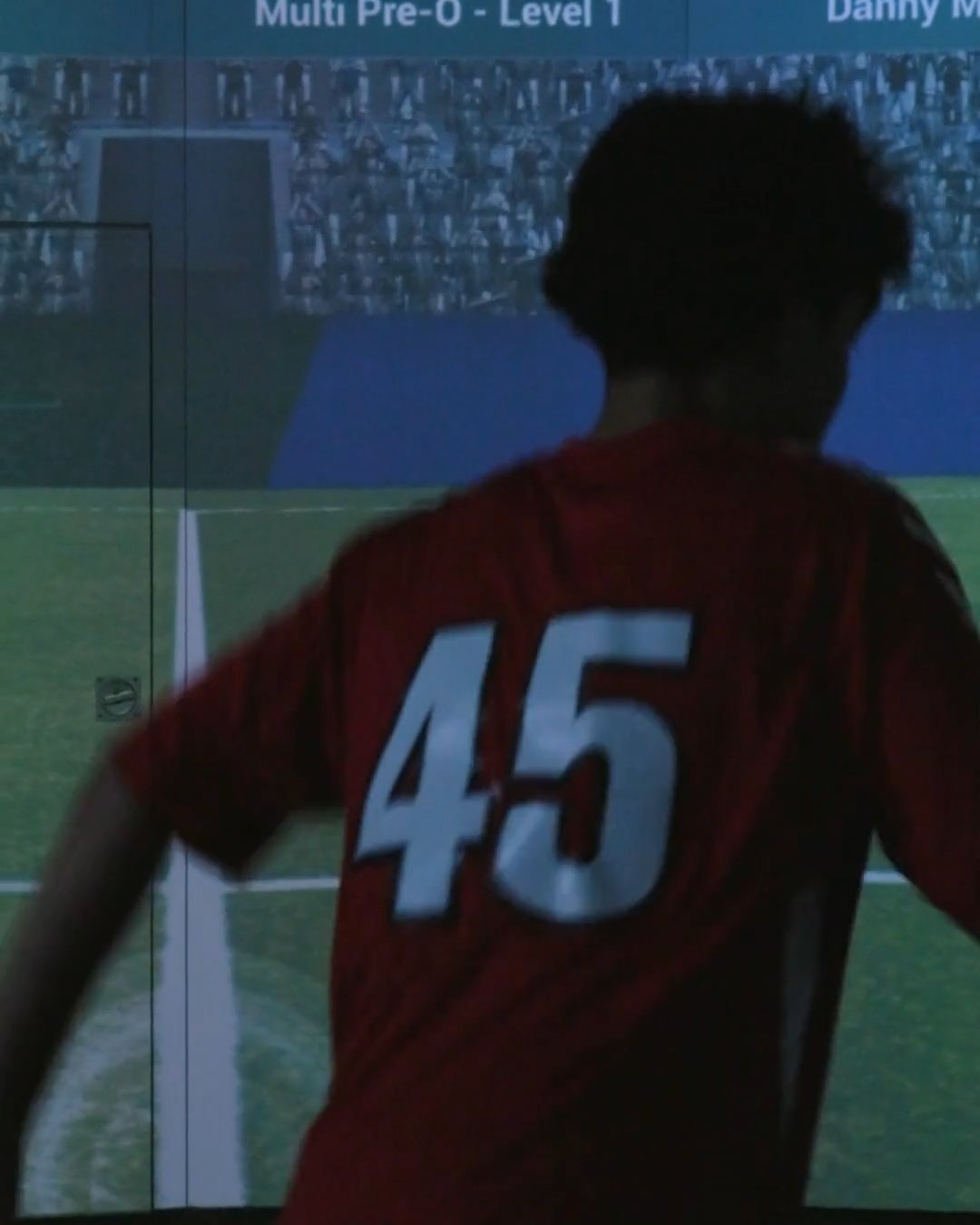 SFA player in the academy red kit facing the SoccerBot360 projection wall