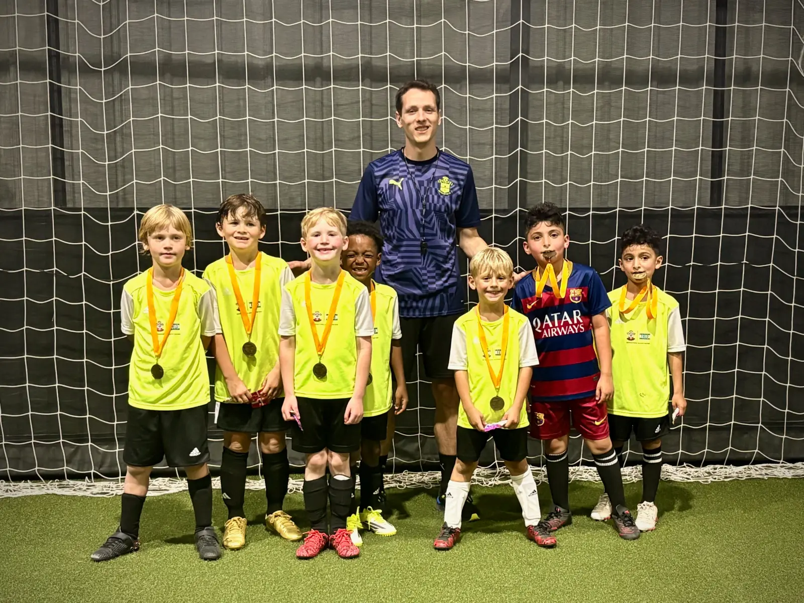 Soccer Field Academy Rec+ youth players with their season-end medals, posed with their coach inside the indoor facility in Bexley, Ohio